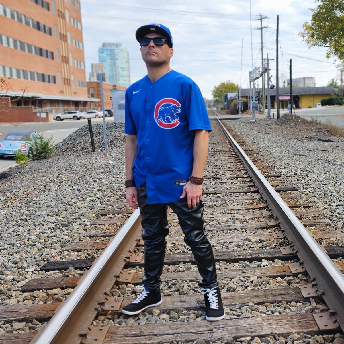 Cosmicus in Chicago Cubs Jersey and faux leather punk pants standing on railroad tracks