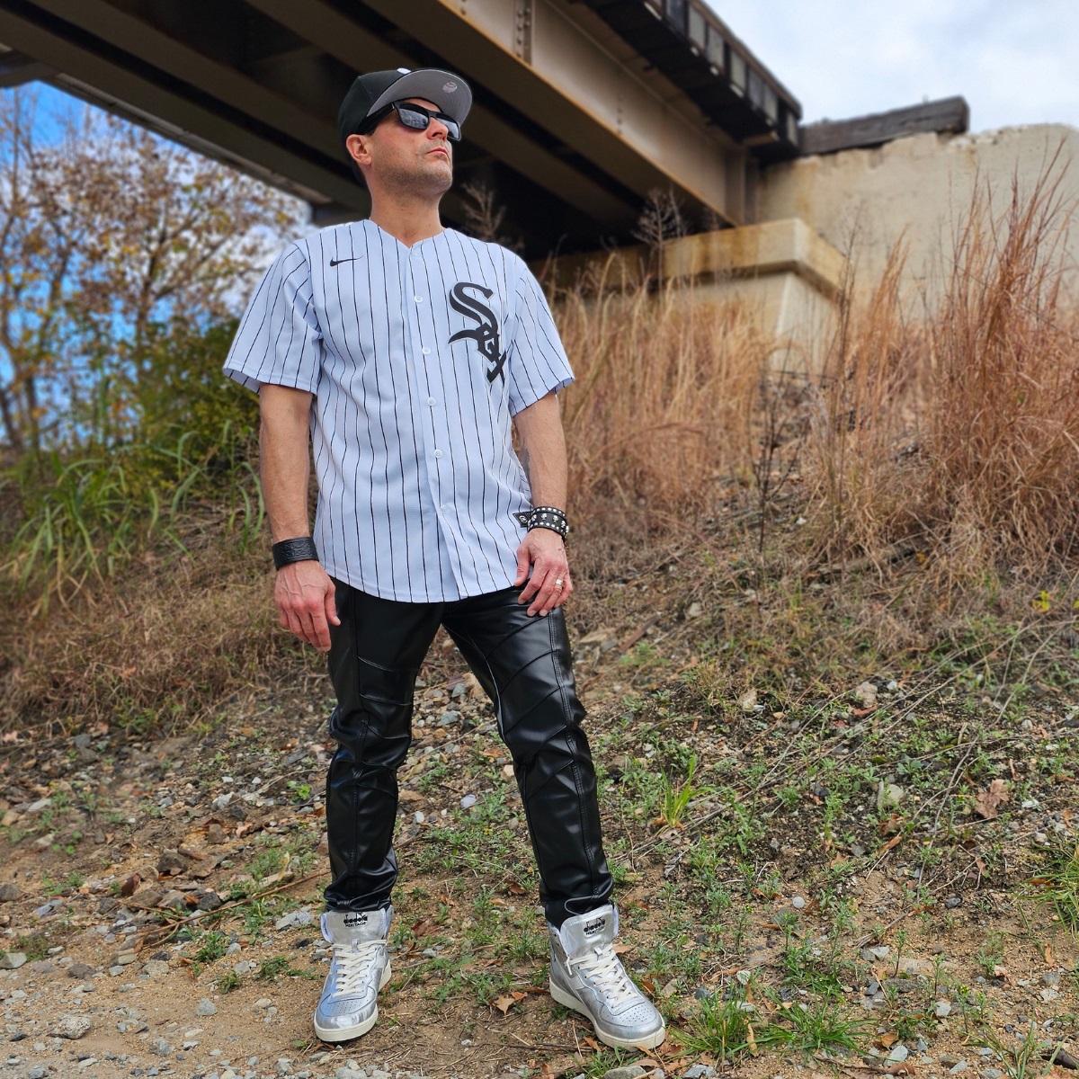 Cosmicus in Chicago White Sox Jersey and faux leather punk pants with shiny diadora high top sneakers by railroad tracks in city