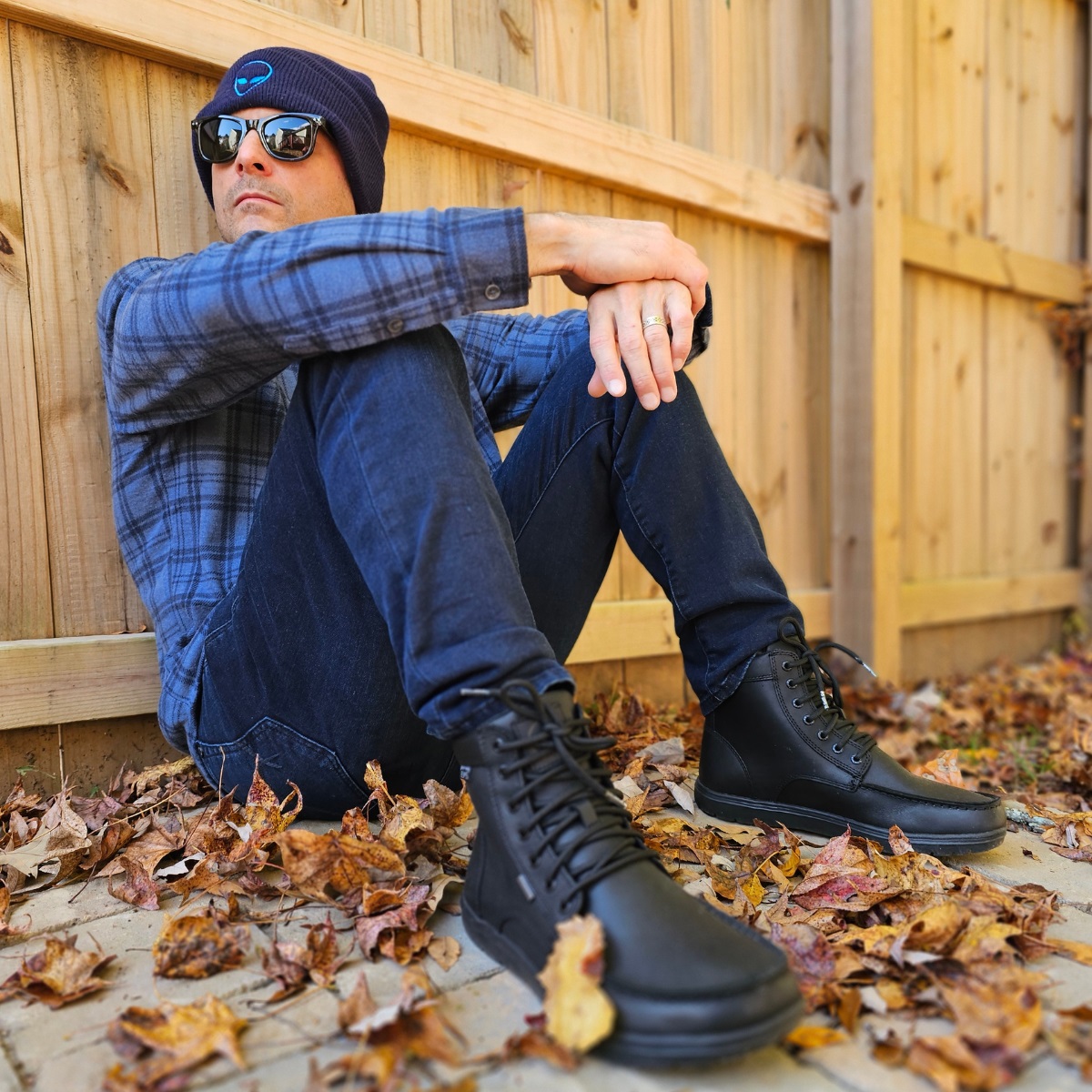 Cosmicus sitting by fence in city with alien hat with boots and flannel